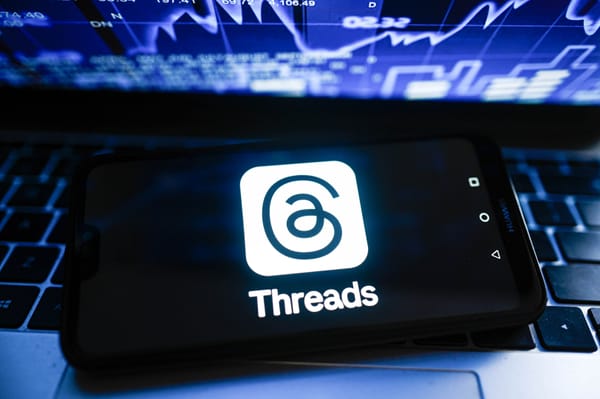 In this photo illustration a Threads logo is displayed on a smartphone with stock market percentages in the background