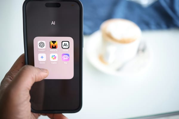 A hand holding a smartphone showing a folder with several AI chatbots, including ChatGPT, Gemini, and Claude