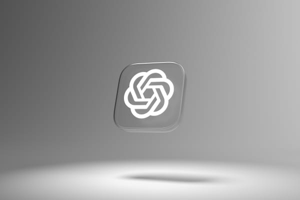The OpenAI logo in white on a gray tile, floating in the air against a gray backdrop